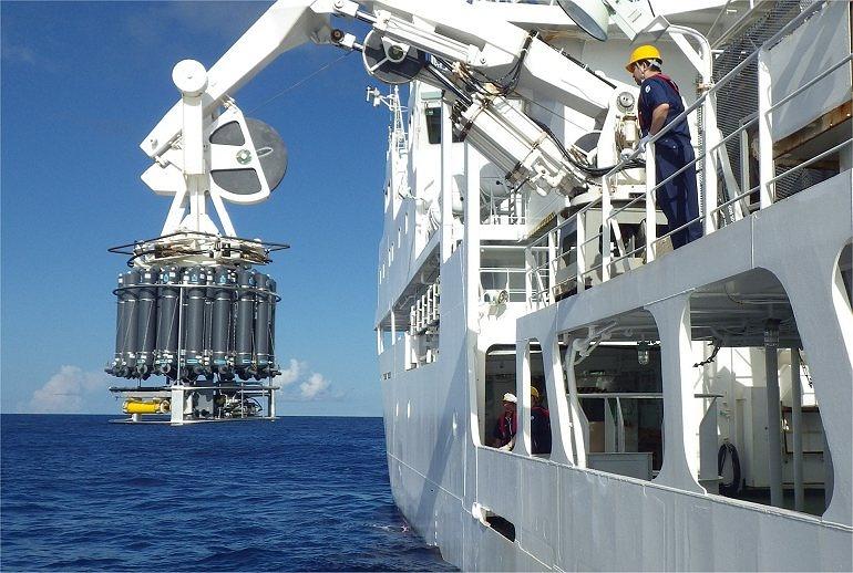 观测人员正用缆绳将CTD和36条採水器连为一体的装置沉入海中