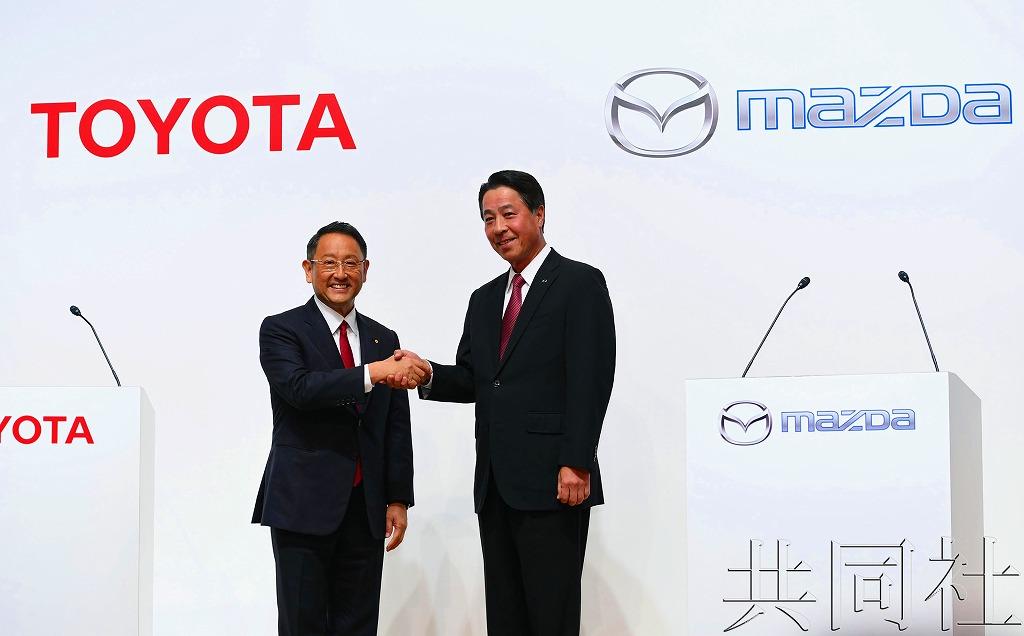 丰田汽车社长丰田章男（左）和马自达社长小饲雅道握手